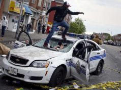 Baltimore rioter on top of broken police car