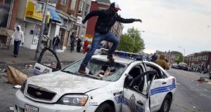 Baltimore rioter on top of broken police car